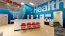 bright interior image of CVS Pharmacy. blue walls, white countertops and red chairs.