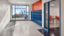 school hallway with orange walls, blue lockers and large bright window