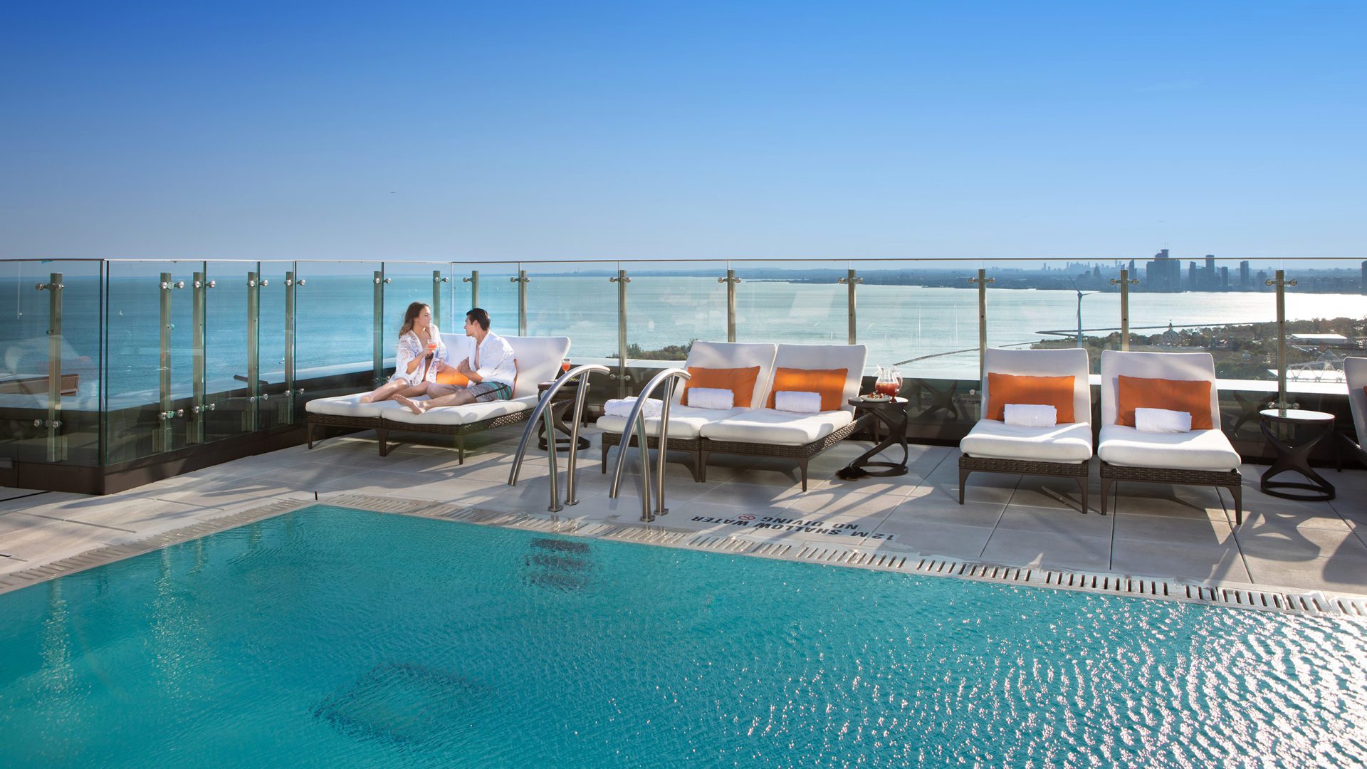 couple lounges at Hotel X Rooftop Pool with view of lake and city landscape
