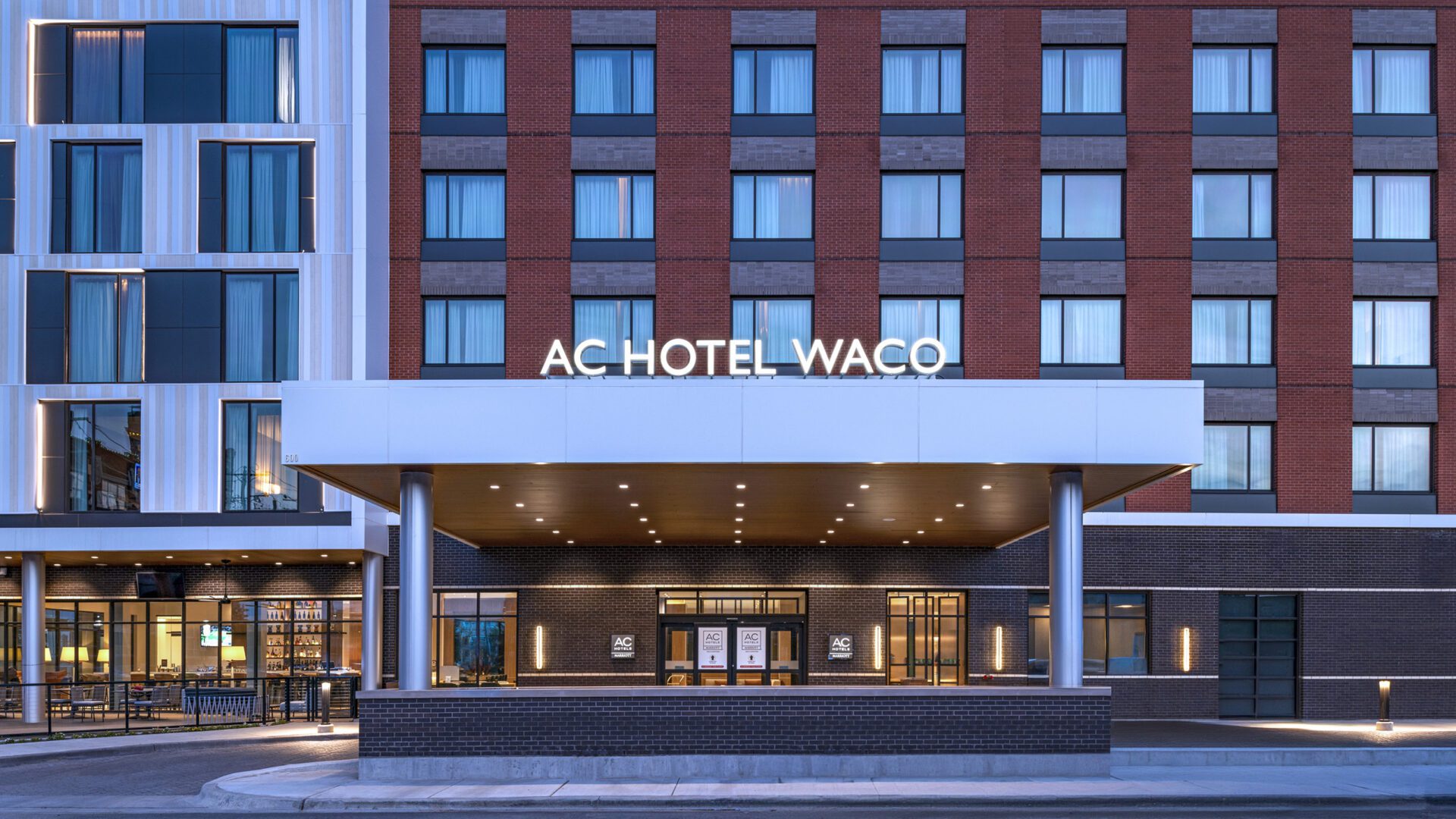 Hotel main entrance exterior with covered entryway and light up sign that reads "AC Hotel Waco"