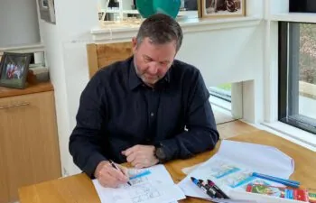 Man sitting on a chair at a desk sketching