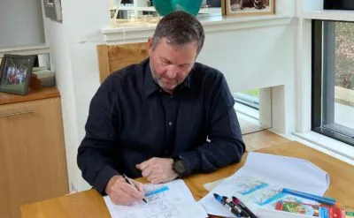 Man sitting on a chair at a desk sketching