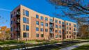 A stylish apartment building showcasing contemporary architecture, landscaped surroundings and pedestrian-friendly pathways.