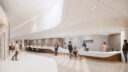 A contemporary interior view showing the reception desk of the Schroeder Ambulatory Centre. Staff and visitors interact in a spacious, well-lit area with modern furnishings.