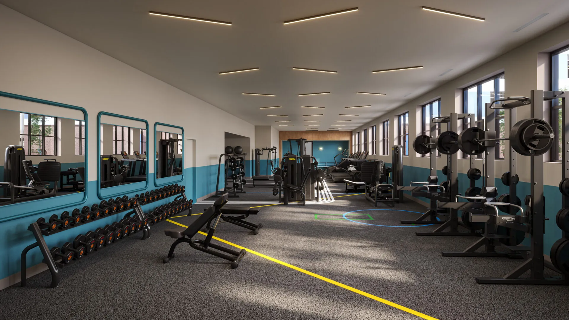 Another view of the gym, highlighting the free weight area and additional equipment. Mirrors line the walls, reflecting the well-lit, spacious interior.