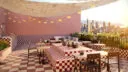 A rooftop terrace with a checkerboard design in red and white tiles. The space includes tables, seating areas, string lights and a panoramic view of the city skyline at sunset.