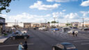 Wide view of a shopping center parking lot with scattered cars and people walking towards stores under a partly cloudy sky.